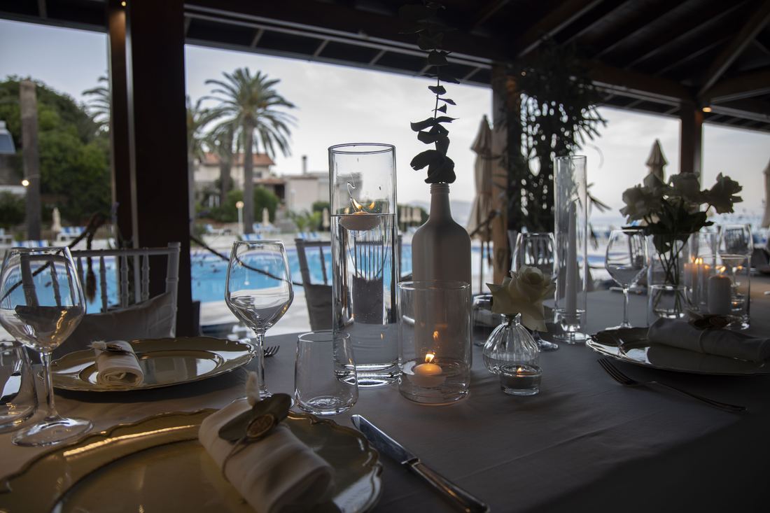 Tavola apparecchiata all'imbrunire con vista sulla piscina e le palme