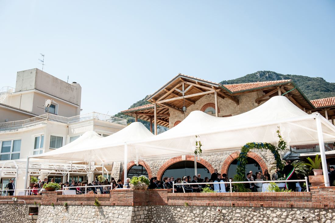 Cerimonia in terrazza sotto le vele bianche, con il promontorio alle spalle