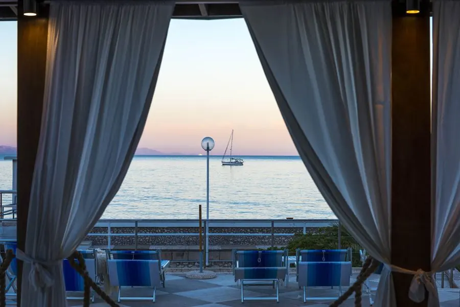 Vista del mare dalla terrazza incorniciata dalle tende
