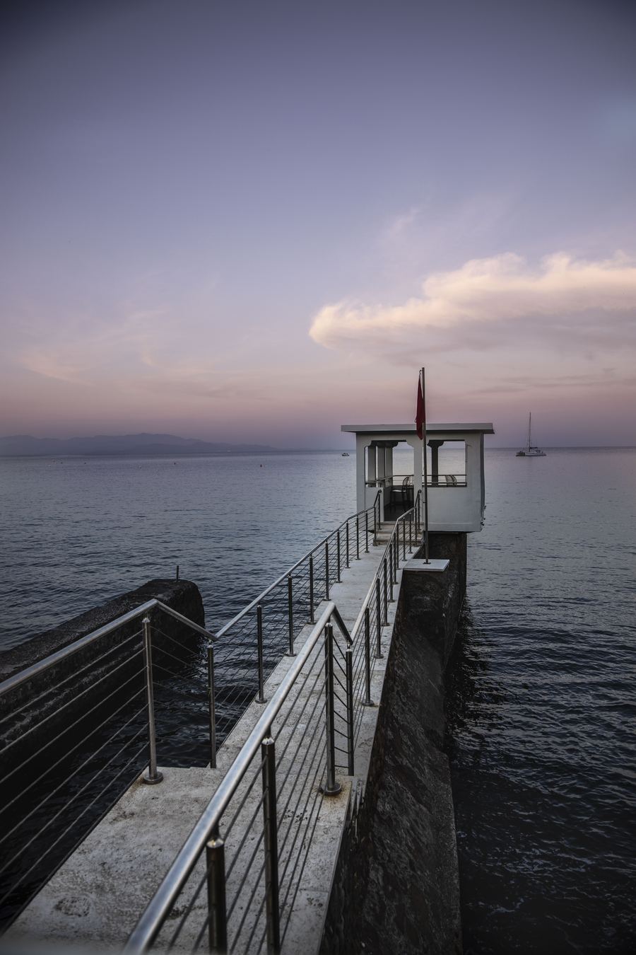 Il pontile con la torretta e una barca a vela all'orizzonte